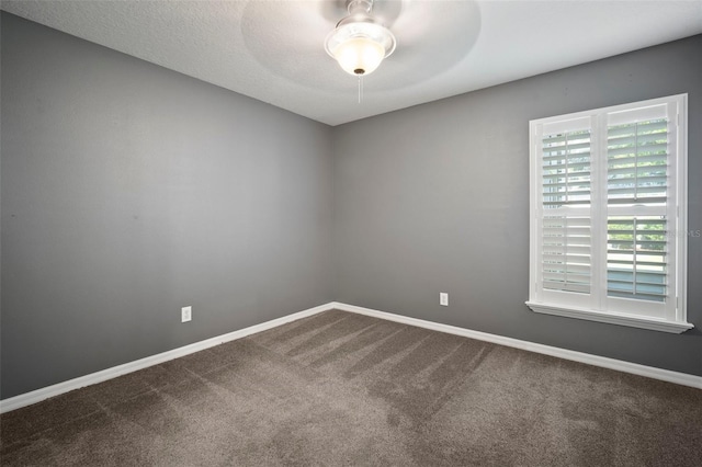 unfurnished room with dark carpet, ceiling fan, and baseboards