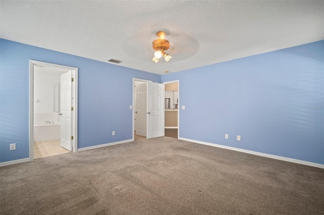 unfurnished bedroom featuring carpet, baseboards, a textured ceiling, ensuite bathroom, and ceiling fan