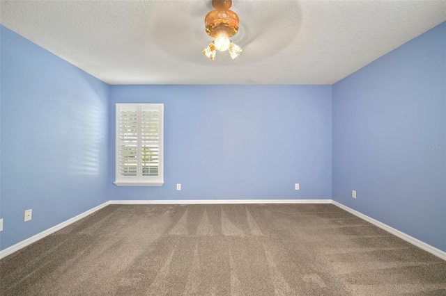 empty room featuring carpet floors, baseboards, and a textured ceiling