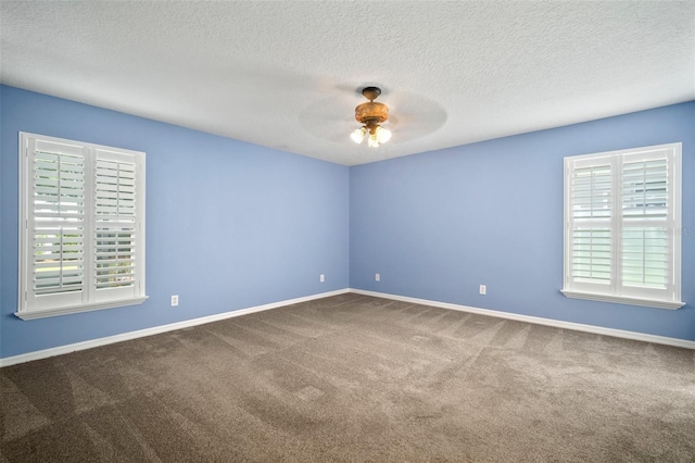 unfurnished room featuring plenty of natural light, ceiling fan, carpet flooring, baseboards, and a textured ceiling