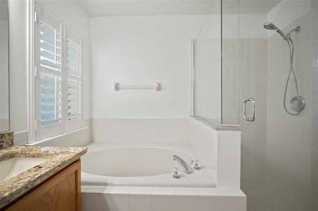 bathroom with a stall shower, a garden tub, and vanity