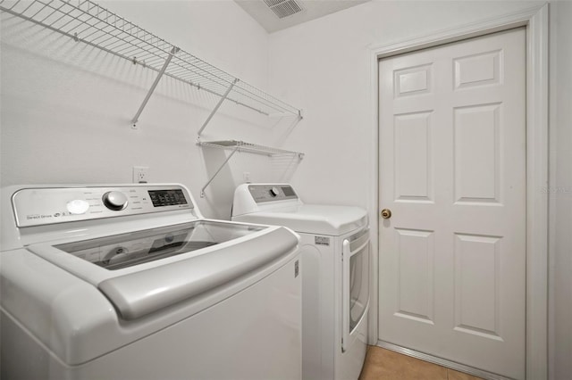 laundry area with washing machine and clothes dryer and light tile patterned floors