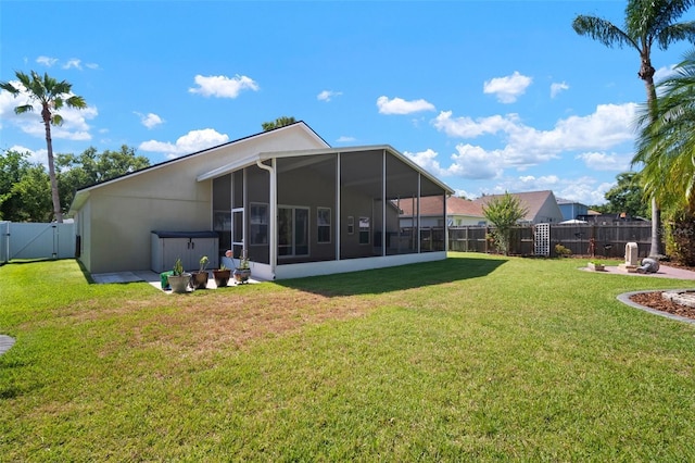 back of house featuring a sunroom, a gate, and stucco siding