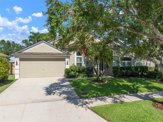 obstructed view of property featuring stucco siding, driveway, a garage, and a front lawn