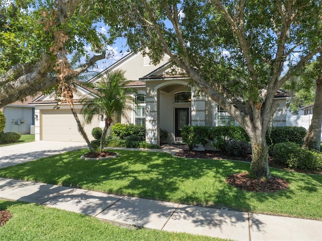 view of front facade with stucco siding, driveway, a garage, and a front lawn