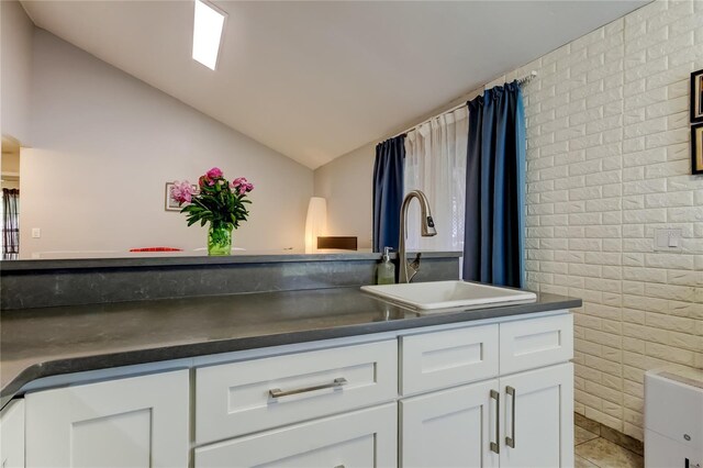 2721 Baird Ct, Palm Harbor, FL 34684 - bathroom with brick wall, lofted ceiling, vanity, and tile patterned flooring