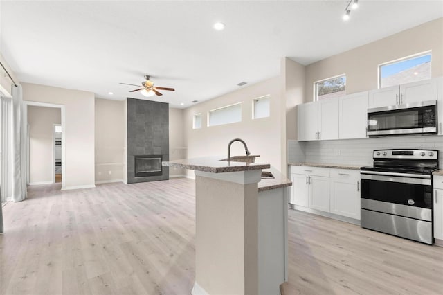 3023 Minuteman Ln, Brandon, FL 33511 - kitchen with stainless steel appliances, a sink, light wood-style flooring, a ceiling fan, and light stone counters