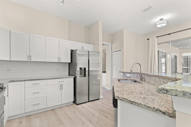 3023 Minuteman Ln, Brandon, FL 33511 - kitchen featuring stainless steel fridge with ice dispenser, a sink, light wood-style flooring, backsplash, and white cabinetry