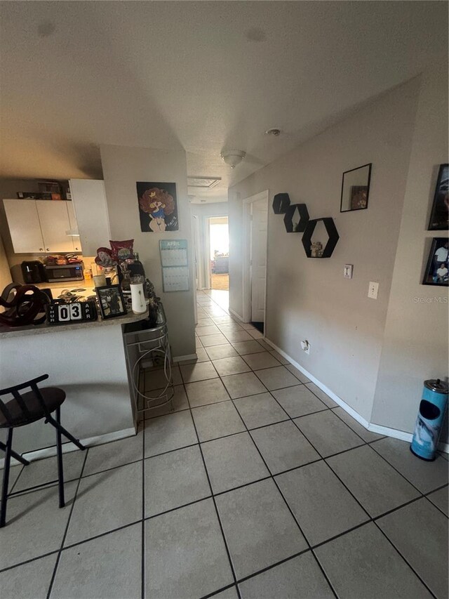 3710 N 57th St, Tampa, FL 33619 - kitchen with light tile patterned floors, baseboards, and white cabinets