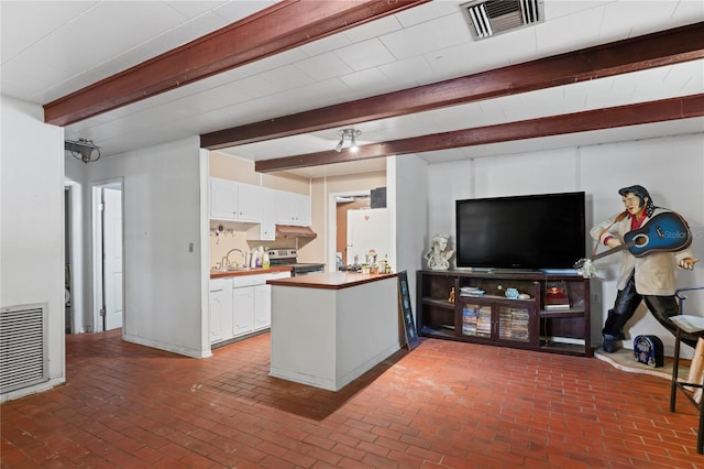 8828 Jasmine Blvd, Port Richey, FL 34668 - kitchen featuring stainless steel range with electric stovetop, beamed ceiling, freestanding refrigerator, brick floors, and a peninsula