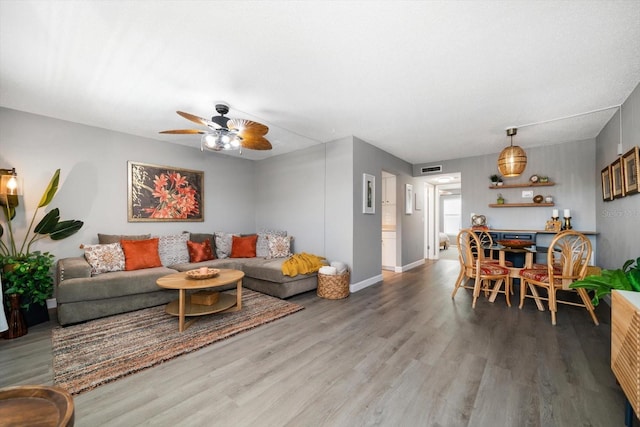 living room with wood finished floors, a ceiling fan, and baseboards