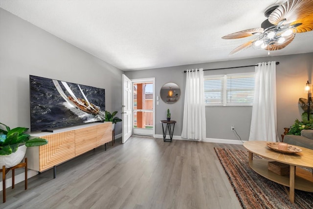 living room featuring wood finished floors, ceiling fan, and baseboards