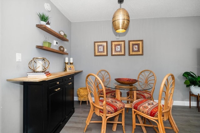 dining space featuring wood finished floors, a textured ceiling, and baseboards