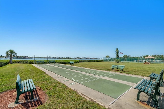 view of community featuring shuffleboard, a lawn, and a water view