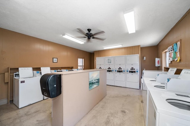 shared laundry with stacked washer / drying machine, washer and clothes dryer, ceiling fan, and wood walls
