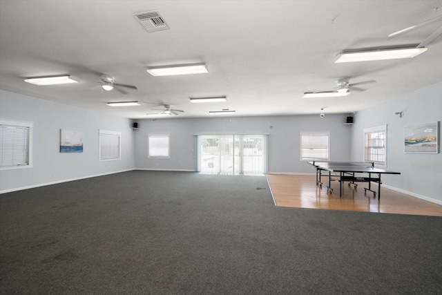 empty room featuring a ceiling fan, dark carpet, plenty of natural light, and baseboards