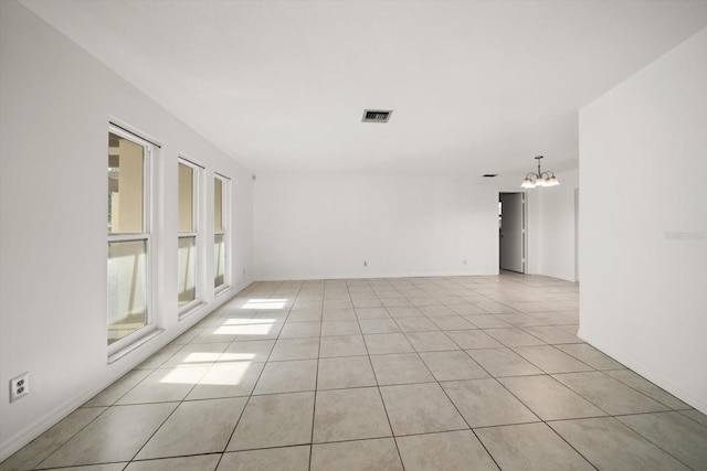 1142 Lancer Ln, Tarpon Springs, FL 34689 - spare room featuring a chandelier, light tile patterned floors, and baseboards