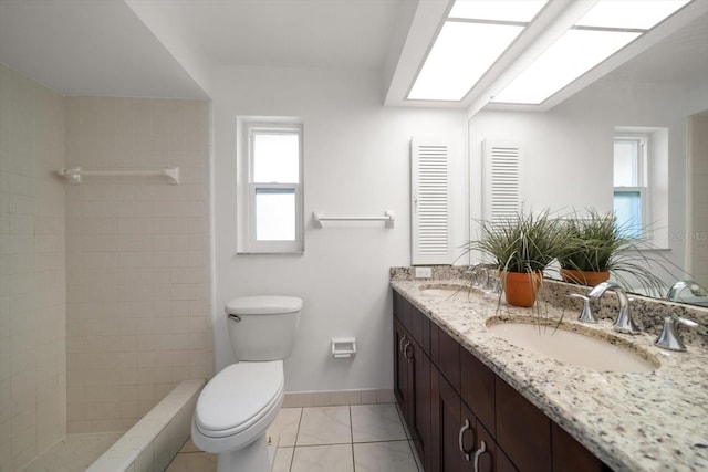 1142 Lancer Ln, Tarpon Springs, FL 34689 - bathroom featuring toilet, double vanity, tile patterned floors, baseboards, and a tile shower
