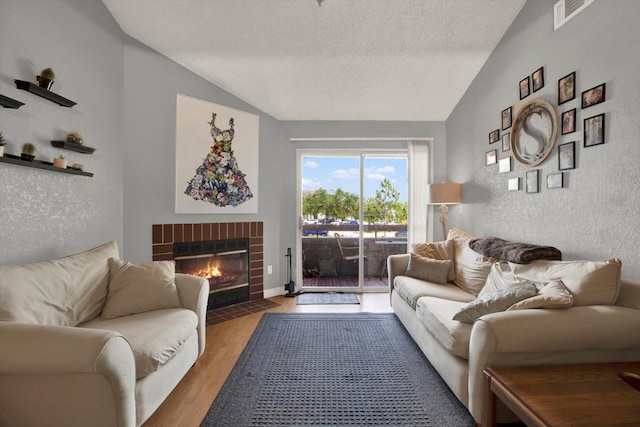 10265 Gandy Blvd N Unit 906, Saint Petersburg, FL 33702 - living room featuring vaulted ceiling, a fireplace, wood finished floors, and a textured ceiling