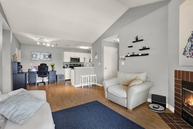 10265 Gandy Blvd N Unit 906, Saint Petersburg, FL 33702 - living area featuring an office area, wood finished floors, a tile fireplace, vaulted ceiling, and baseboards