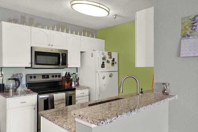 10265 Gandy Blvd N Unit 906, Saint Petersburg, FL 33702 - kitchen with stainless steel appliances, a textured ceiling, light stone counters, a peninsula, and white cabinets