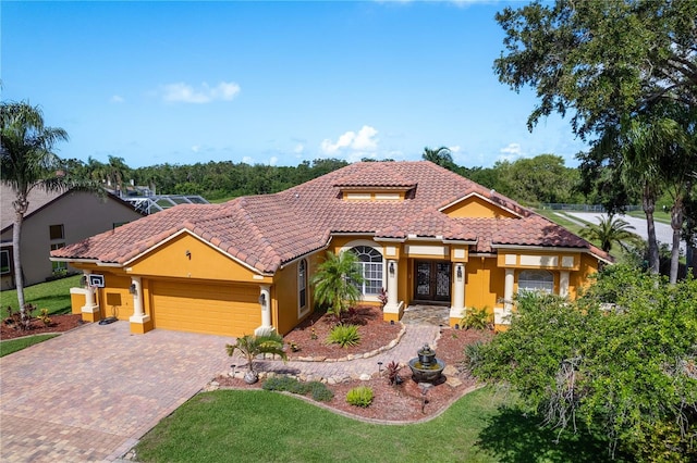 800 Belted Kingfisher Dr S, Palm Harbor, FL 34683 - mediterranean / spanish house with a tile roof, an attached garage, stucco siding, decorative driveway, and a front yard