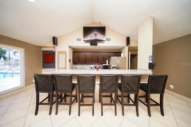 1400 Gandy Blvd N Unit 1705, Saint Petersburg, FL 33702 - kitchen with stainless steel fridge with ice dispenser, a kitchen breakfast bar, light countertops, and vaulted ceiling