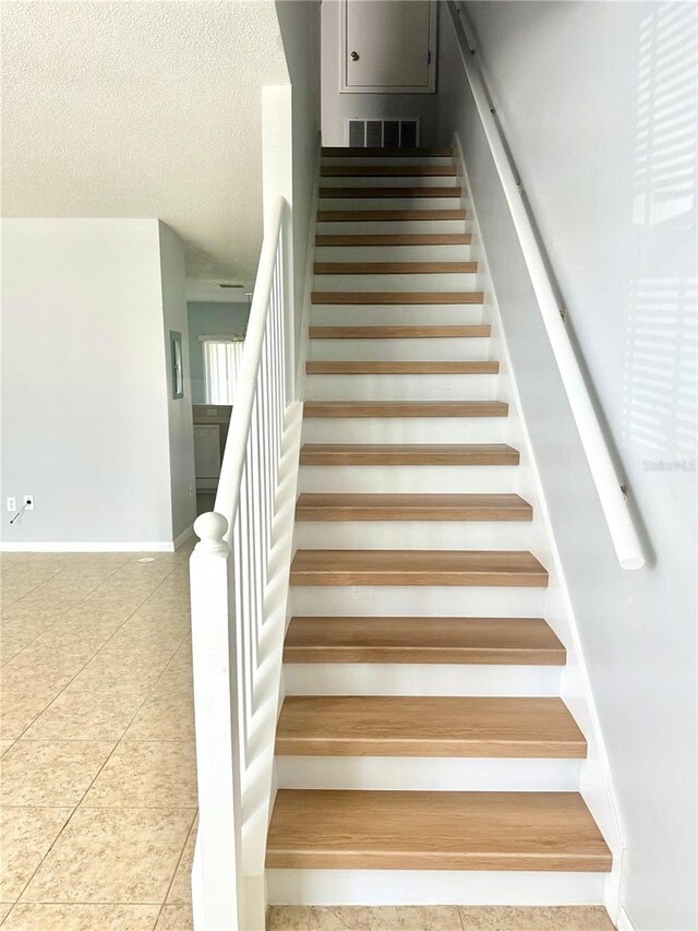 6025 Osprey Lake Cir, Riverview, FL 33578 - stairs with tile patterned floors, baseboards, and a textured ceiling