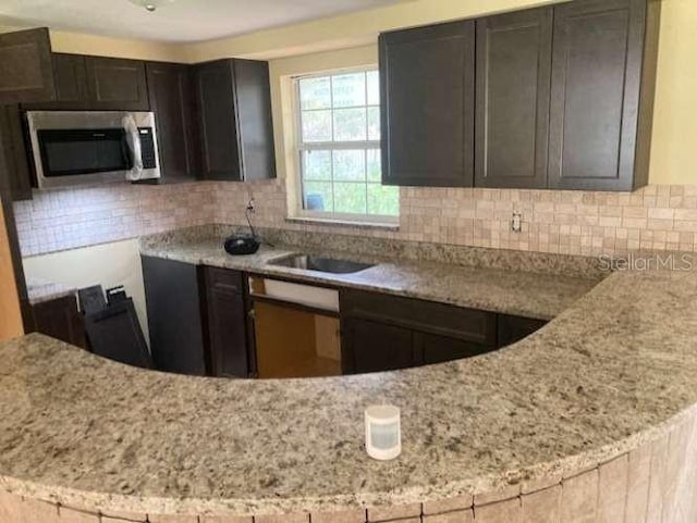 17220 Estes Rd, Lutz, FL 33548 - kitchen with stainless steel microwave, decorative backsplash, and light stone counters
