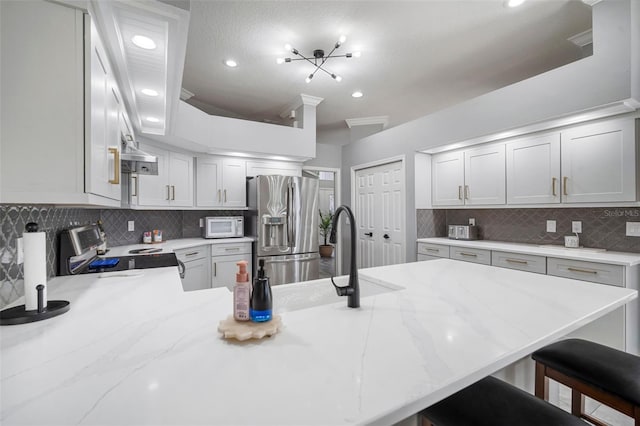 2903 Manor Ridge Pl, Valrico, FL 33596 - kitchen featuring stainless steel appliances, decorative backsplash, a breakfast bar, a peninsula, and light stone counters