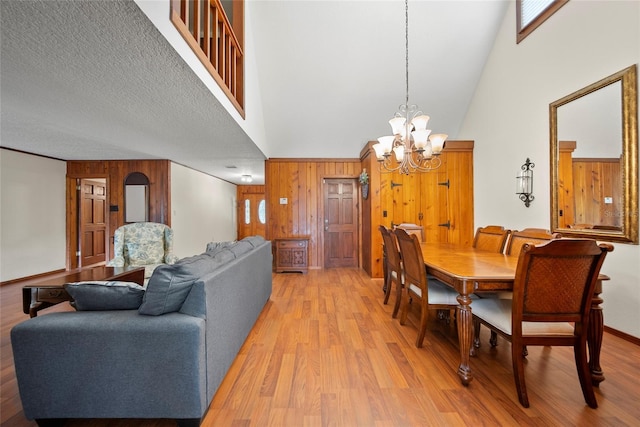 8011 N Mobley Rd, Odessa, FL 33556 - dining room with high vaulted ceiling, wooden walls, a chandelier, and light wood-style floors