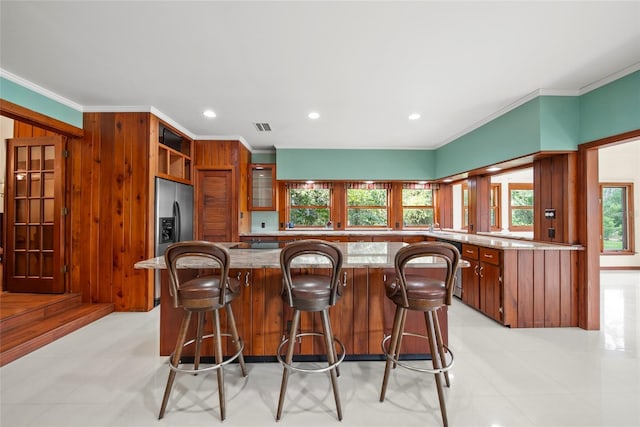 8011 N Mobley Rd, Odessa, FL 33556 - kitchen featuring stainless steel refrigerator with ice dispenser, crown molding, brown cabinets, a breakfast bar area, and recessed lighting