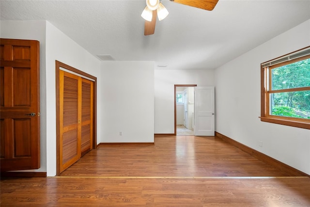 8011 N Mobley Rd, Odessa, FL 33556 - unfurnished bedroom with a closet, wood finished floors, baseboards, and ceiling fan