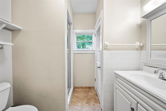 8011 N Mobley Rd, Odessa, FL 33556 - bathroom featuring toilet, vanity, a shower stall, tile walls, and a wainscoted wall