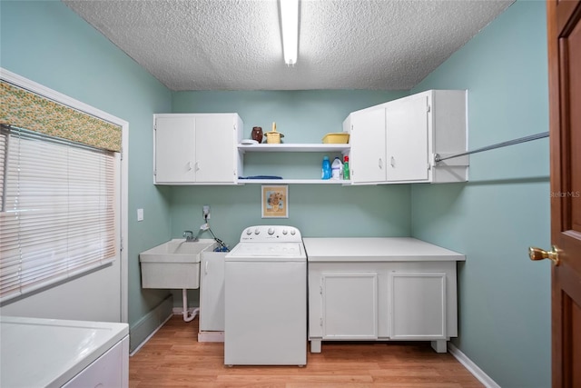 8011 N Mobley Rd, Odessa, FL 33556 - laundry room with washer / dryer, cabinet space, light wood finished floors, a textured ceiling, and baseboards