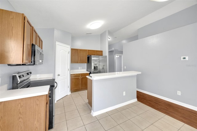 kitchen featuring stainless steel appliances, light tile patterned floors, light countertops, brown cabinetry, and lofted ceiling