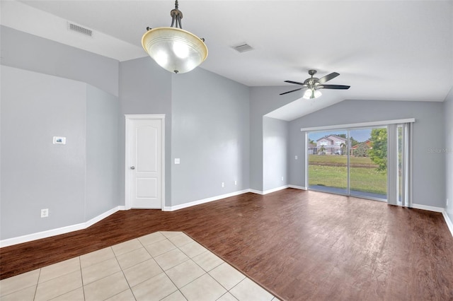 empty room with wood finished floors, lofted ceiling, a ceiling fan, and baseboards