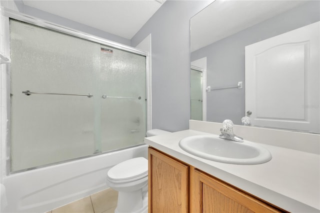 bathroom with tile patterned floors, toilet, vanity, and combined bath / shower with glass door