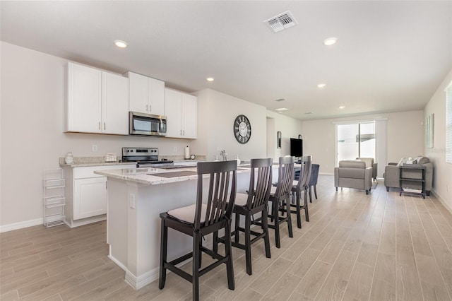 7119 Amelia River Dr, Parrish, FL 34219 - kitchen with appliances with stainless steel finishes, light wood-style floors, open floor plan, white cabinets, and recessed lighting