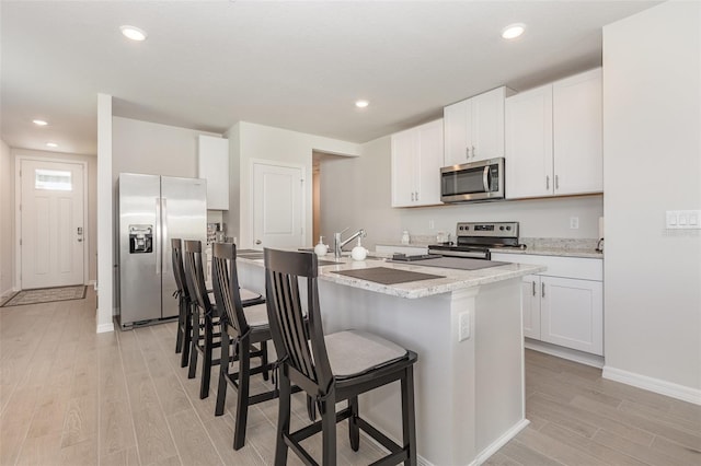 7119 Amelia River Dr, Parrish, FL 34219 - kitchen featuring stainless steel appliances, light wood-type flooring, a breakfast bar area, baseboards, and an island with sink