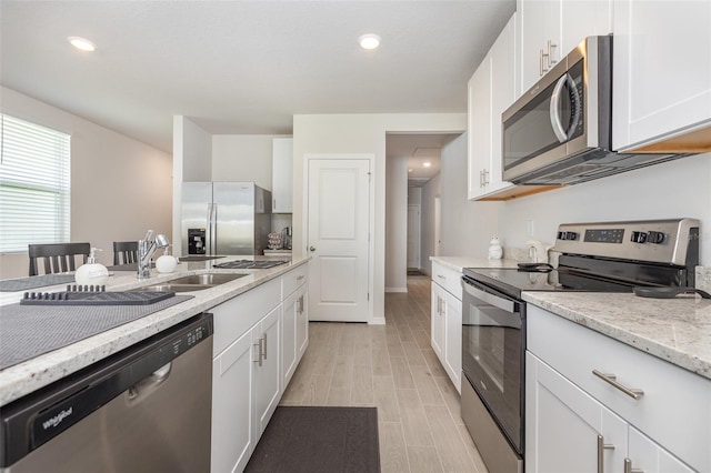 7119 Amelia River Dr, Parrish, FL 34219 - kitchen featuring stainless steel appliances, a sink, white cabinets, light stone counters, and recessed lighting