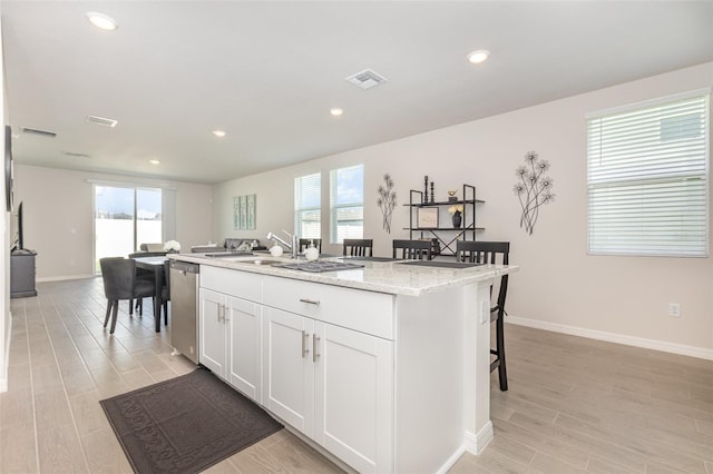 7119 Amelia River Dr, Parrish, FL 34219 - kitchen with a center island with sink, white cabinetry, baseboards, recessed lighting, and light wood-type flooring