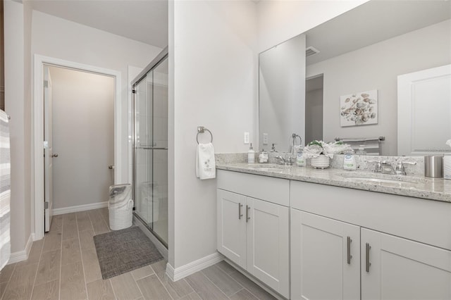 7119 Amelia River Dr, Parrish, FL 34219 - full bath with double vanity, a shower stall, wood finish floors, and baseboards