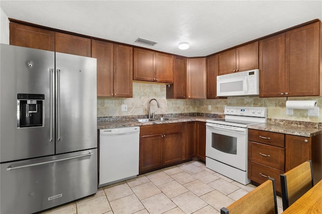2646 61st Ave N, Saint Petersburg, FL 33714 - kitchen with white appliances, a sink, decorative backsplash, light tile patterned floors, and brown cabinets