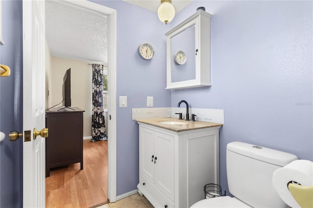 2646 61st Ave N, Saint Petersburg, FL 33714 - bathroom with toilet, vanity, a textured ceiling, wood finished floors, and baseboards