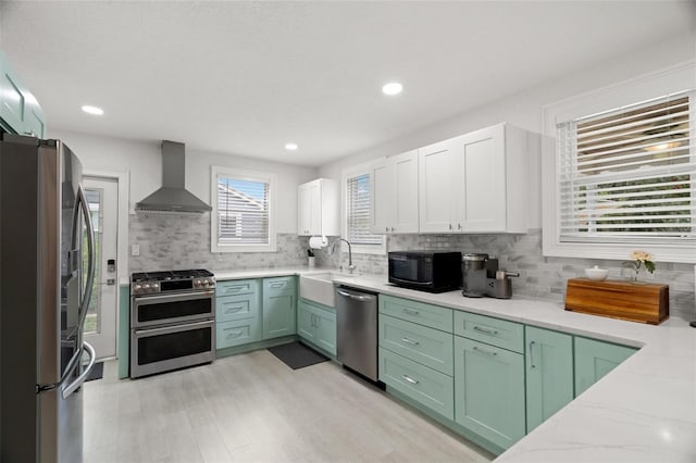 1003 W Indiana Ave, Tampa, FL 33603 - kitchen featuring wall chimney range hood, stainless steel appliances, green cabinets, backsplash, and recessed lighting