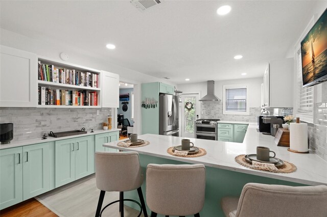 1003 W Indiana Ave, Tampa, FL 33603 - kitchen featuring wall chimney range hood, stainless steel appliances, tasteful backsplash, a peninsula, and recessed lighting
