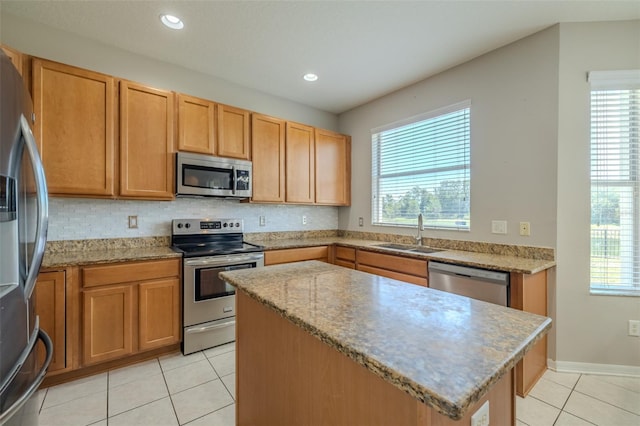 7852 Stoney Hill Dr, Wesley Chapel, FL 33545 - kitchen featuring stainless steel appliances, a sink, light tile patterned floors, a center island, and backsplash