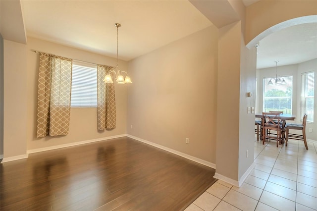 7852 Stoney Hill Dr, Wesley Chapel, FL 33545 - unfurnished dining area featuring a chandelier, arched walkways, light wood finished floors, and baseboards