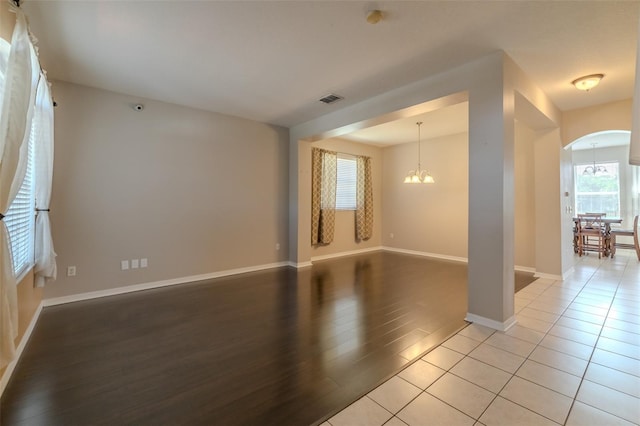 7852 Stoney Hill Dr, Wesley Chapel, FL 33545 - empty room featuring a chandelier, arched walkways, light wood-style floors, baseboards, and a smoke detector